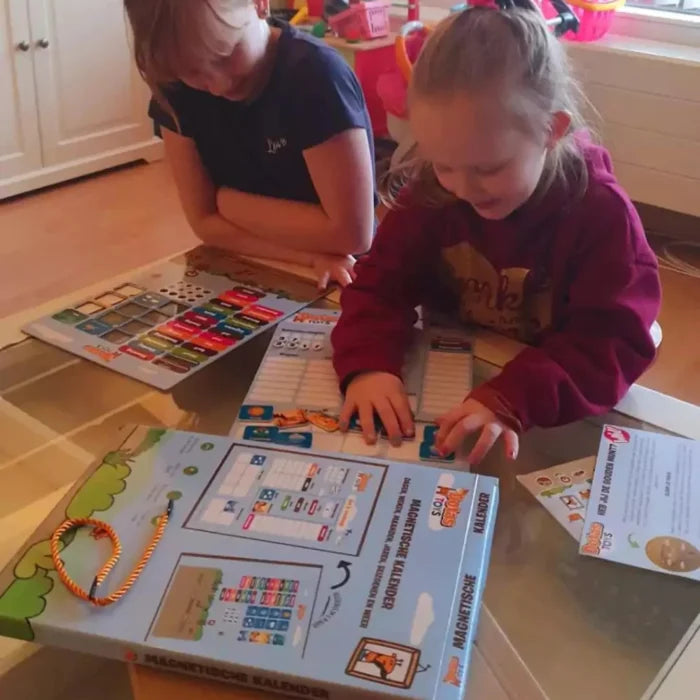 Kinderen spelen met de DotasToys magnetische kalender en zetten dag, datum en weer met magneten