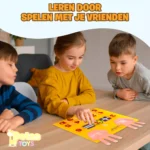 Drie kinderen zitten rondom een houten tafel en spelen met het gele Dotas Toys vilt rekenbord met roze vingervormen en rode cijfers, onder de tekst ‘Leren door spelen met je vrienden